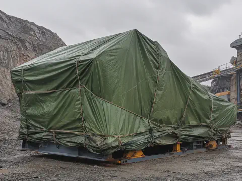Green tarpaulin cover protecting mining machinery outdoors