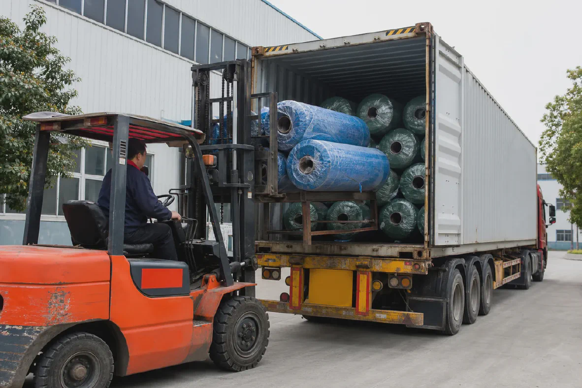 Forklift loading woven fabric rolls into a container