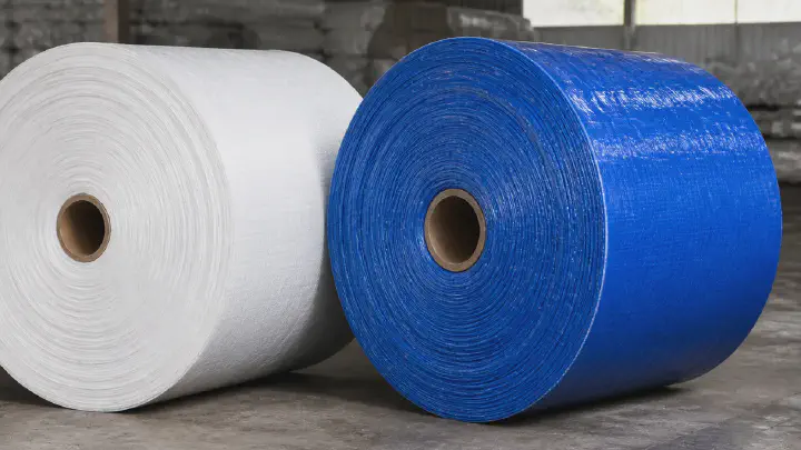 White PP woven roll beside a blue PE laminated tarpaulin roll