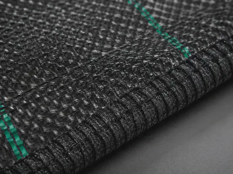 Close-up texture of black PP woven ground cover fabric for agricultural weed control